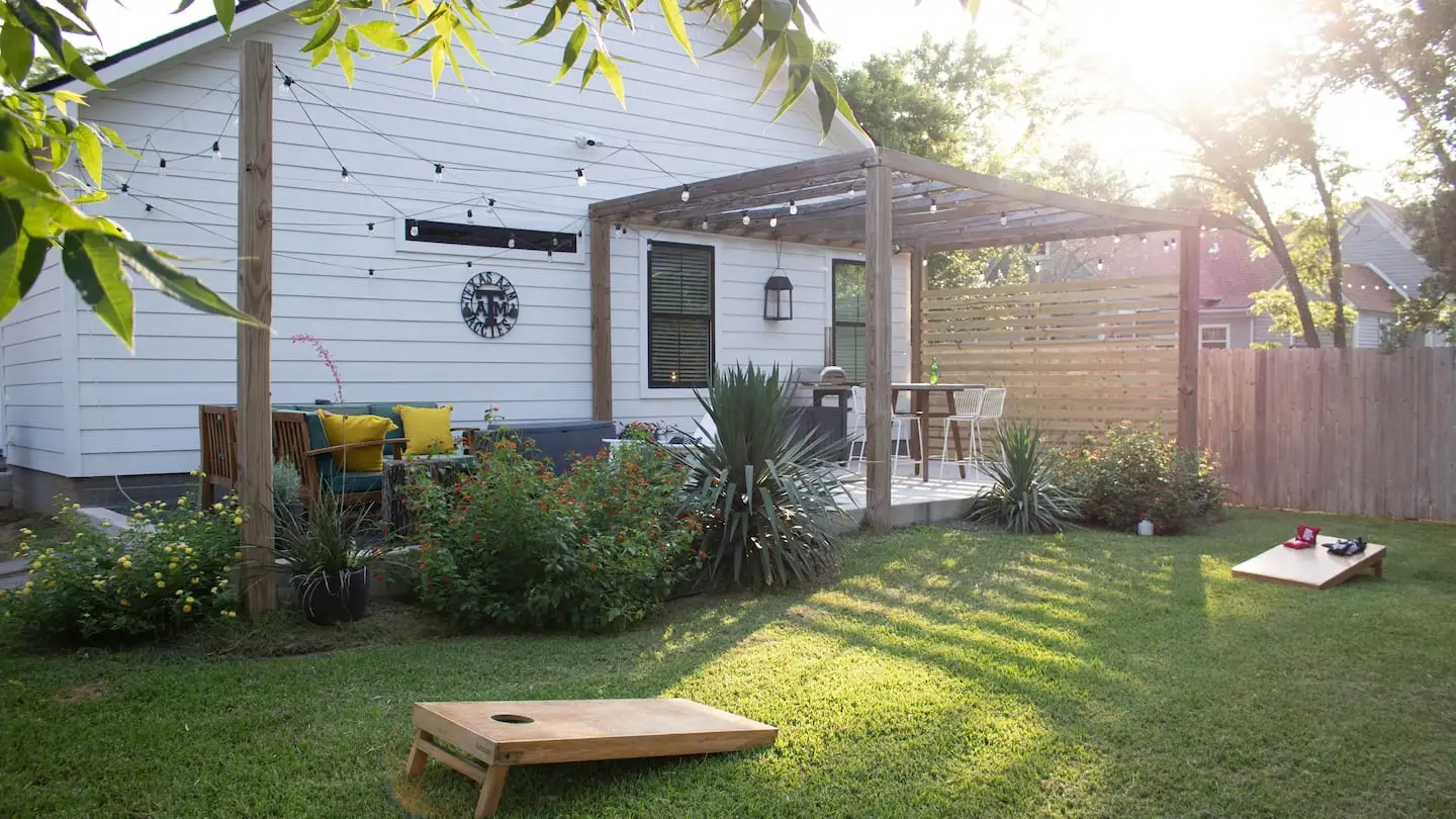 Sunny backyard with cornhole and patio